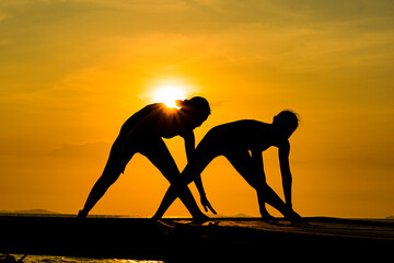 silhouette of two people. silhouette of a woman doing yoga on the beach. silhouette of a woman doing yoga.