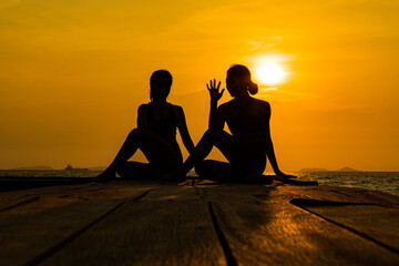 Fototapeta na wymiar silhouette of two people. silhouette of a woman doing yoga on the beach. silhouette of a woman doing yoga.
