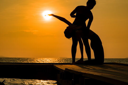 silhouette of two people. silhouette of a woman doing yoga on the beach. silhouette of a woman doing yoga.