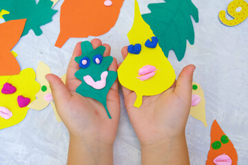 Autumn crafts. Child making colorful fun leaves from paper and plasticine. Back to school. Ideas for children's art and drawing