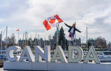 Girl waving Canada flag on the top of sign
