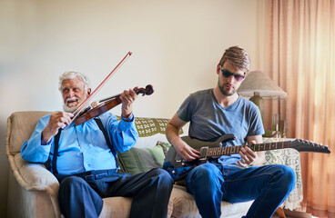 Music bridges the generation gap. Shot of a young man playing the electric guitar while his elderly...
