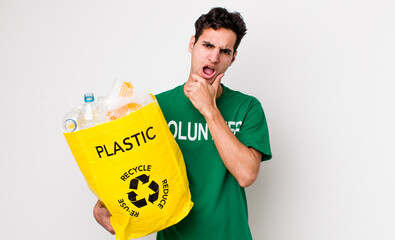 handsome hispanic man with mouth and eyes wide open and hand on chin. ecology concept