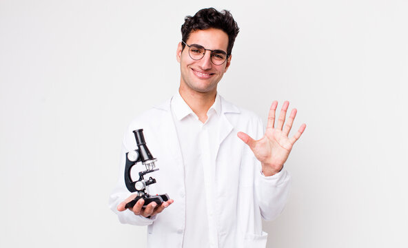 handsome hispanic man smiling and looking friendly, showing number five.. scientist with microscope concept