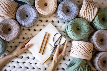 Closeup creative female hands holding elegant notepad surrounded by multicolored ribbon yarn