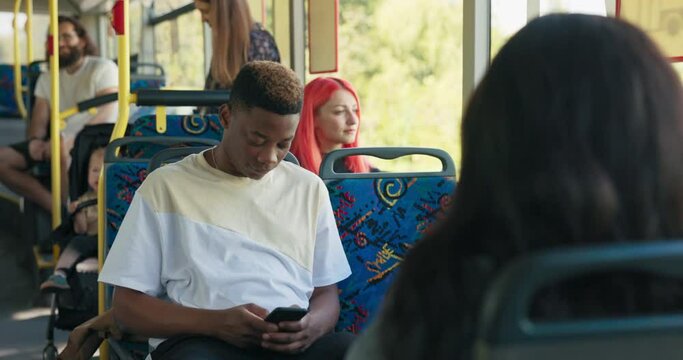 A Young Man In A White T-shirt Is Sitting On A Bus Chair, Traveling From Work To Home, To School, To A Meeting With Friends, Holding A Phone In His Hands, Writing Messages