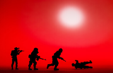 Fototapeta na wymiar Silhouetted toy army plastic soldiers organised with a red background, war image