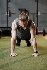 Obraz premium Strong fit young man doing push-ups on gym floor to warm-up before training