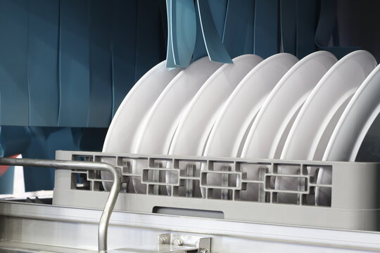 The automatic dishwasher with white clean dishes in basket .For restaurant.