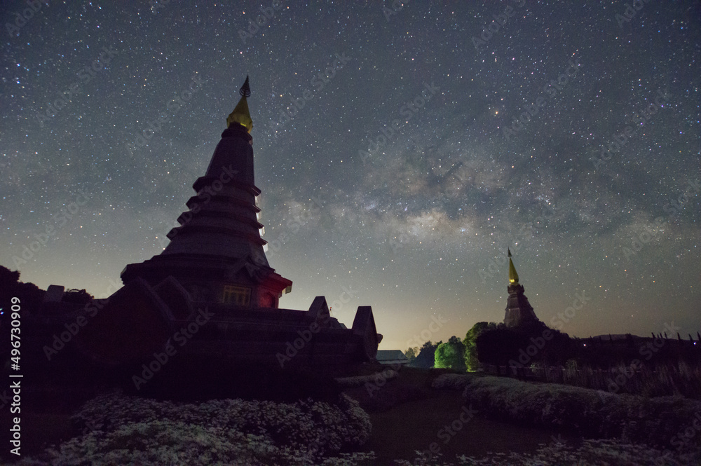 Wall mural the milky way galaxy over a sacred temple at doi inthanon national park, chiang mai, thailand. starr