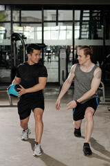 Fototapeta na wymiar Fitness trainer showing client how to do deep forward lunges with medicine ball