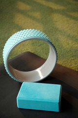 Turquoise yoga wheel and foam block on mat in gym