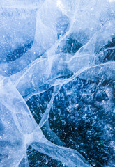 Frozen ice background. Texture of the blue ice with glowing air bubbles. Winter abstract background. Frozen Baikal lake. Ice cracks. Vertical