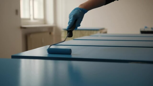 Female hand painting cabinet doors with blue paint and roller