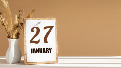 january 27. 27th day of month, calendar date.White vase with dead wood next to cork board with numbers. White-beige background with striped shadow. Concept of day of year, time planner, winter month