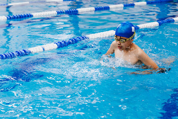 latin child boy swimmer wearing cap and goggles in a swimming training holding On Starting Block In the Pool in Mexico Latin America	