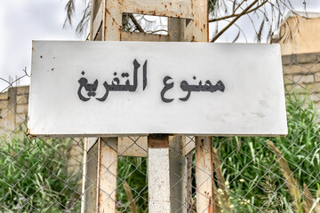 Landfill prohibited Arabic inscription wooden billboard panel hanged on a an electric post in the streets of Algiers.