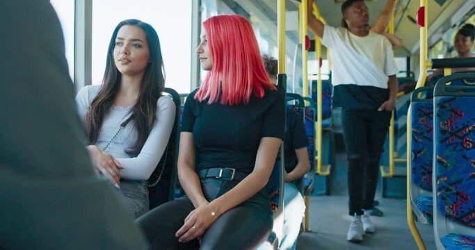 A summer afternoon in public transportation. Young people move by vehicle to home, college. Two women friends are sitting and talking, gossiping, taking the bus to go shopping.