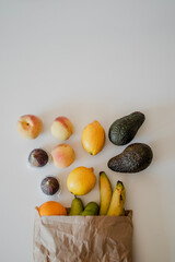 A variety of fruits in a crafted paper bag are lying on the table