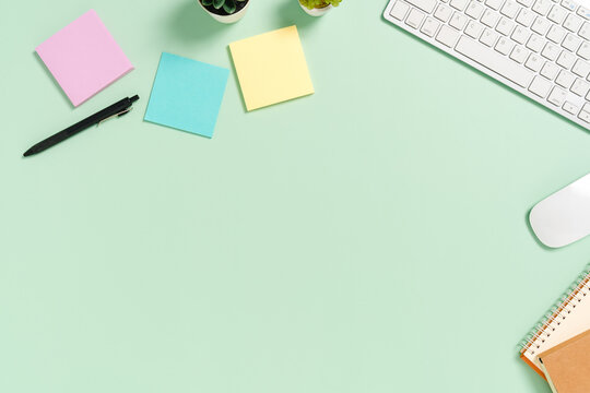 Minimal work space - Creative flat lay photo of workspace desk. Top view office desk with keyboard, mouse and book on pastel green color background. Top view with copy space, flat lay photography.