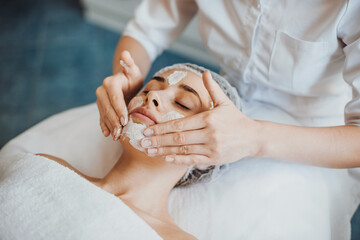 Beautiful woman receiving facial massage and spa treatment at beauty salon. Cosmetology beauty procedure. Facial skincare. Facial treatment. Young woman skin