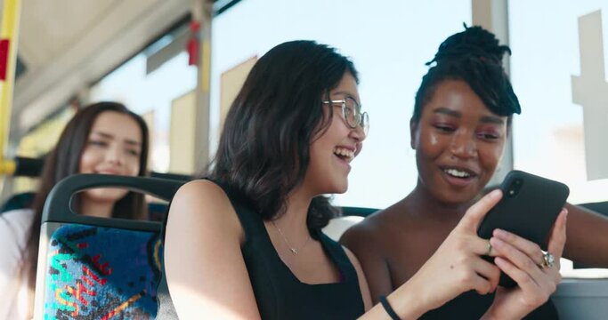 Two pretty women of different nationalities ride the bus, students return from university in a public transport vehicle, look at photos, browse social media, laugh, gossip