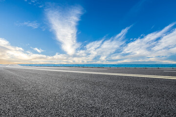 Empty asphalt road near the lake under blue sky. road and sky background.
