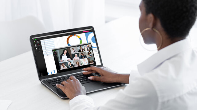 Business telecommuting. Global video call. Virtual interview. Woman working on laptop discussing financial statistics report with professional team on screen in digital office.