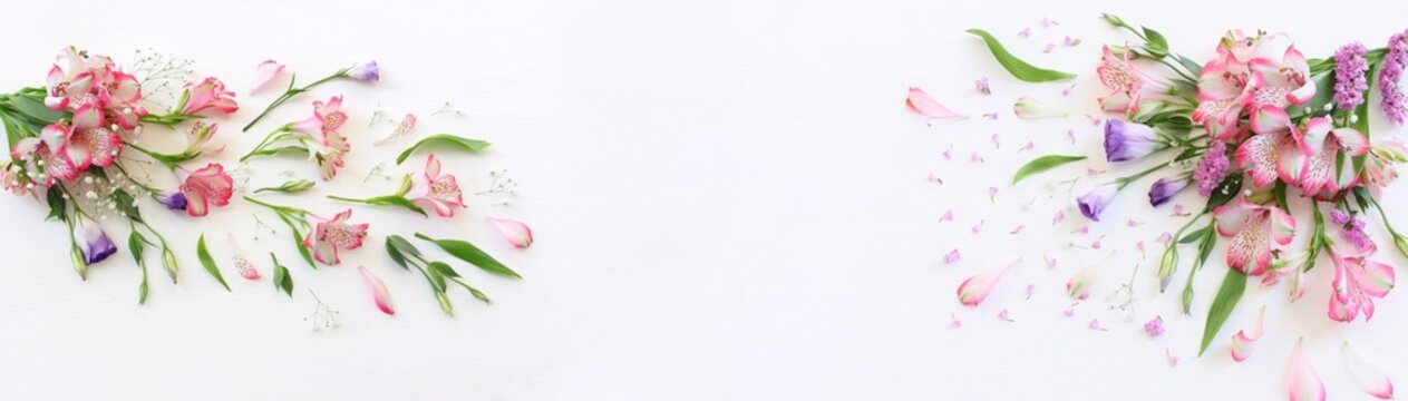 Top view image of pink and purple flowers composition over wooden white background .Flat lay