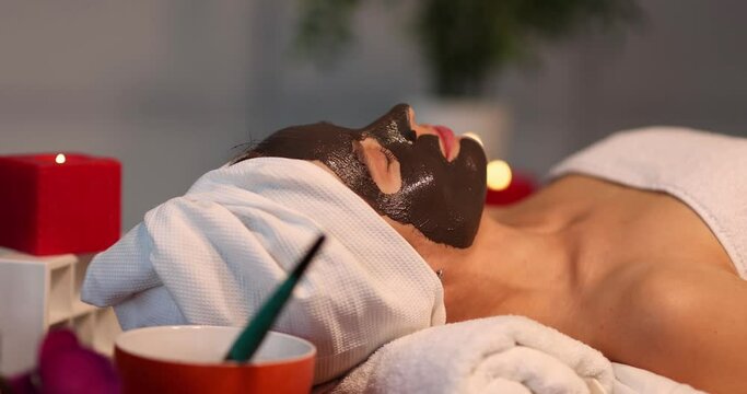 Woman with rejuvenating clay face mask in spa