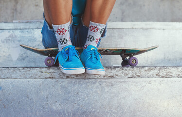 Learn to skate. Cropped of a young woman sitting on her skateboard.