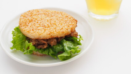 白い皿に盛られた焼肉ライスバーガーとグラスに入った日本茶