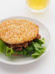 白い皿に盛られた焼肉ライスバーガーとグラスに入った日本茶