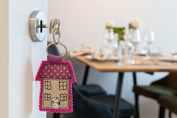 Open door to a new home with key and cute home shaped keychain. Mortgage, investment, real estate, property and new home concept