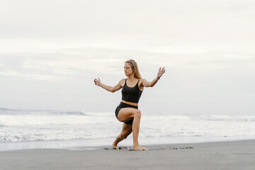 Sporty woman doing mountain climber exercise - run in plank to burn fat. Sunset beach, blue sky background. Healthy lifestyle at tropical island yoga retreat, outdoor activity, family summer vacation.