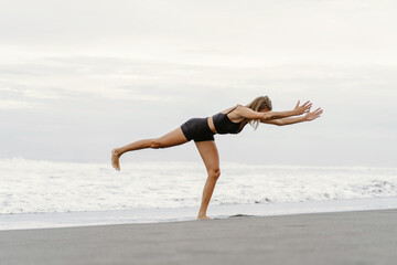 Sporty woman doing mountain climber exercise - run in plank to burn fat. Sunset beach, blue sky...