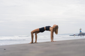 Sporty woman doing mountain climber exercise - run in plank to burn fat. Sunset beach, blue sky...