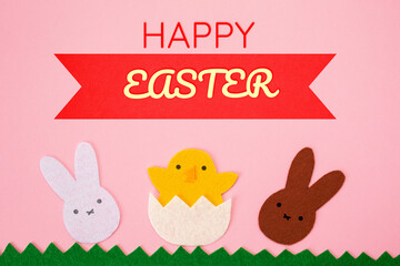 Happy Easter. Cut out the felt applications of white and brown rabbits and the chicken hatched from the egg. Pink background. Flat lay
