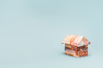 Purchase of housing. Close up of paper origami house made of Russian rubles. Light blue background with copy space. The concept of mortgages and real estate rentals