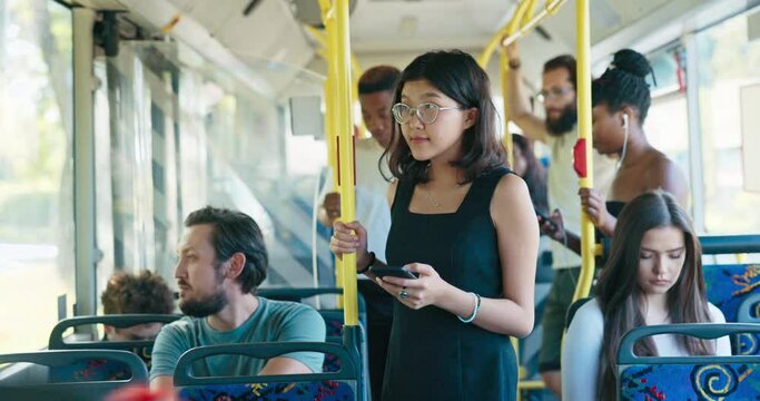 Bus stands at downtown bus stop woman with glasses taking public transportation clings to railing, looks at phone writes back to friends, browses social media occupie time during the long ride home