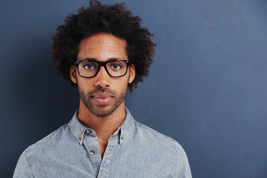 So you think youre smart. Portrait of a handsome young man wearing glasses on a gray background.