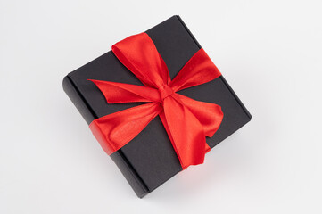 Free floating black gift box with red ribbon isolated on white. Holiday concept