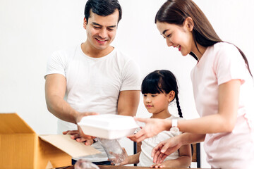 Happy smiling asian family father and mother with little asian girl having fun putting empty recycle plastic bottle garbage and reduce ecology environment into the recycle box