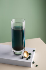 Green detox drink with spirulina in a glass and pills on a minimalistic composition. Vitamins, health and self care concept