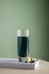 Green detox drink with spirulina in a glass and pills on a minimalistic composition. Vitamins, health and self care concept