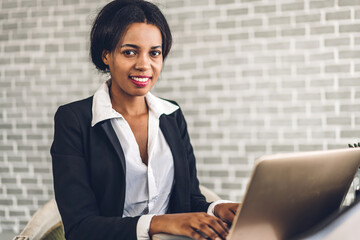 Portrait of smiling happy african american black woman relaxing using technology of laptop computer while sitting on table.Young creative african girl working at home.work from home concept