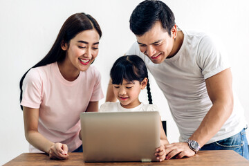 Portrait enjoy happy smiling love asian family father and mother with little asian girl learning and looking at laptop computer studying with online education e-learning system with teacher at home