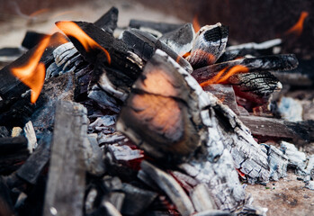 A brightly burning bonfire with a red flame made from wood in an outdoor grill.An adventurous lifestyle in travel. Active weekend recreation in the wild outdoors.