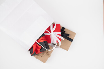 Naklejka premium Different gift boxes falling out from paper bag isolated on white background, top view
