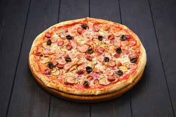 Pizza with various kind of thin sausages, pickled cucumber, olives and onion